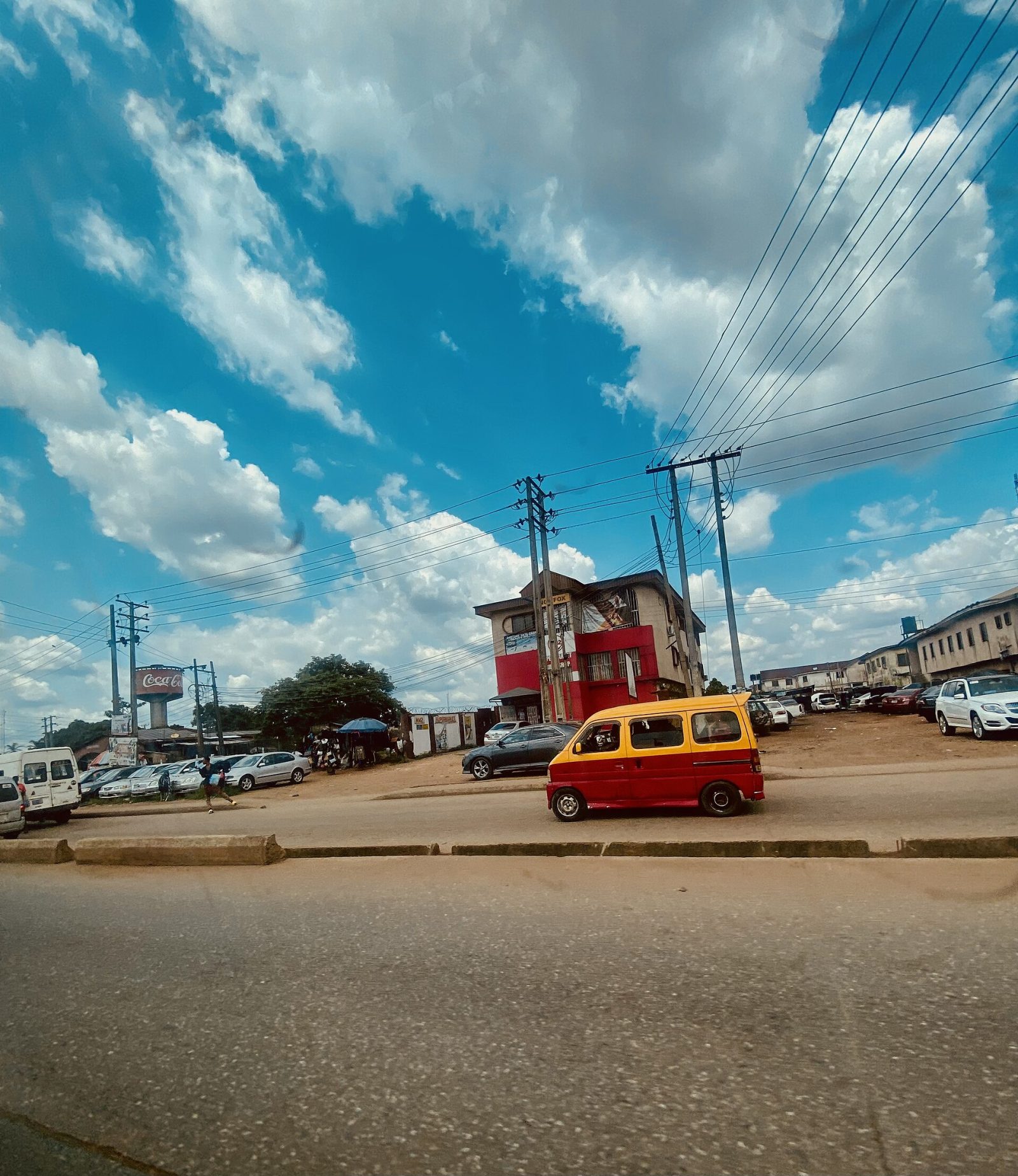 Benin City street with public transit, buildings and overhead power infrastructure
